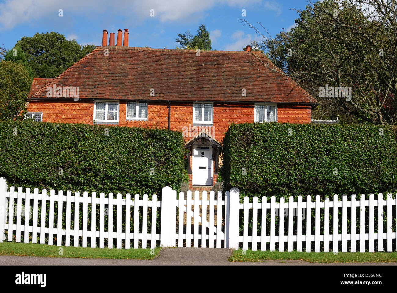 Sol carrelé et brique cottage derrière picket fence à Chiddingfold. Surrey. L'Angleterre Banque D'Images