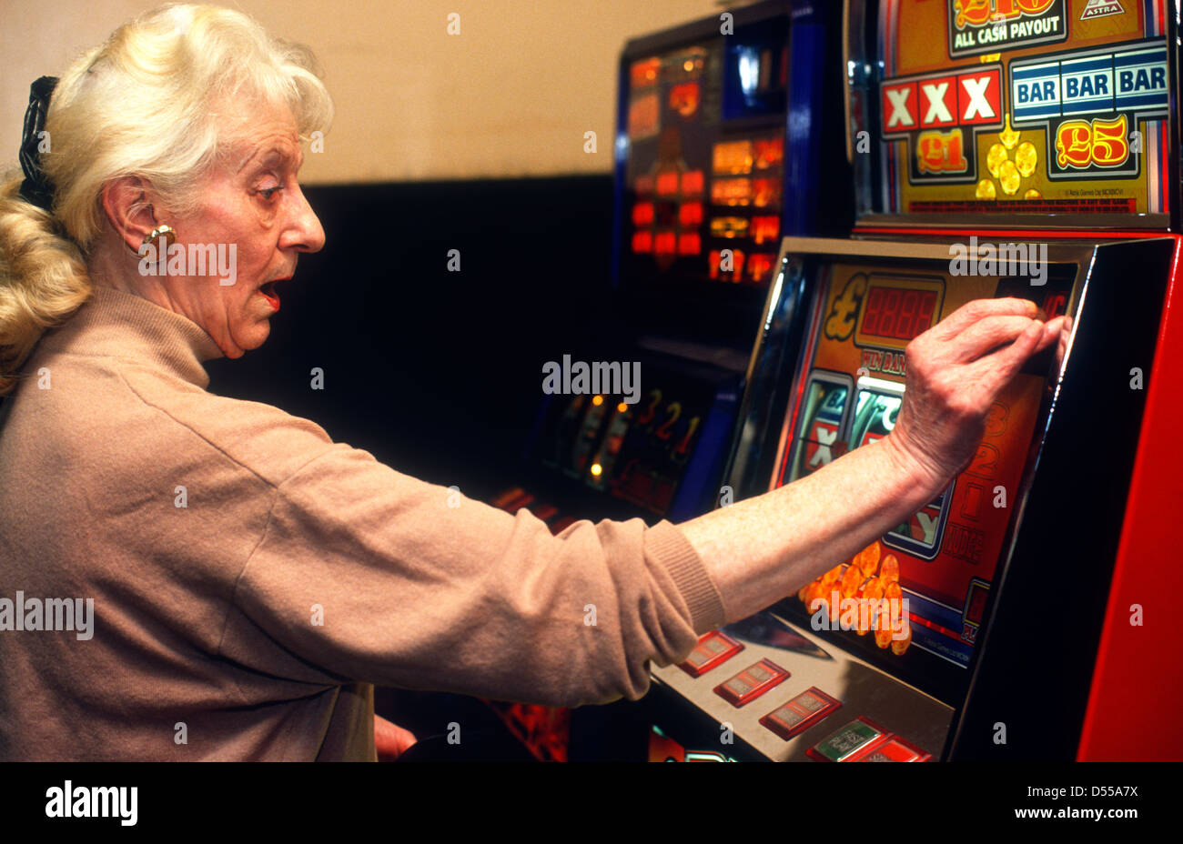 Femme âgée jouer slot machine en salle de bingo, Hounslow, Middlesex, Royaume-Uni. Banque D'Images