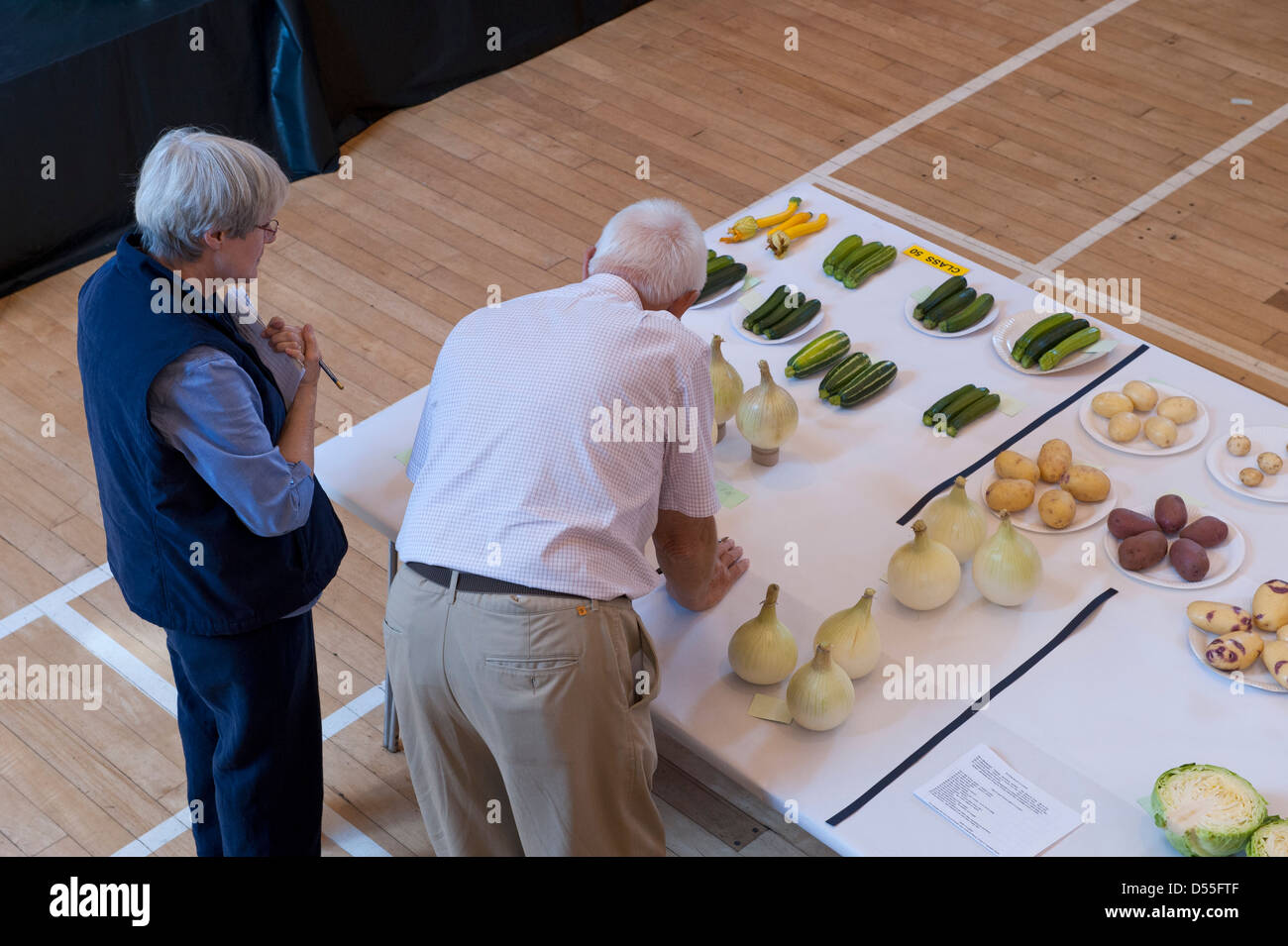 2 juges évaluent la qualité des entrées de légumes à Burley Gardeners' salon annuel - Queen's Hall, Burley-en-Wharfedale, West Yorkshire, Angleterre, Royaume-Uni. Banque D'Images