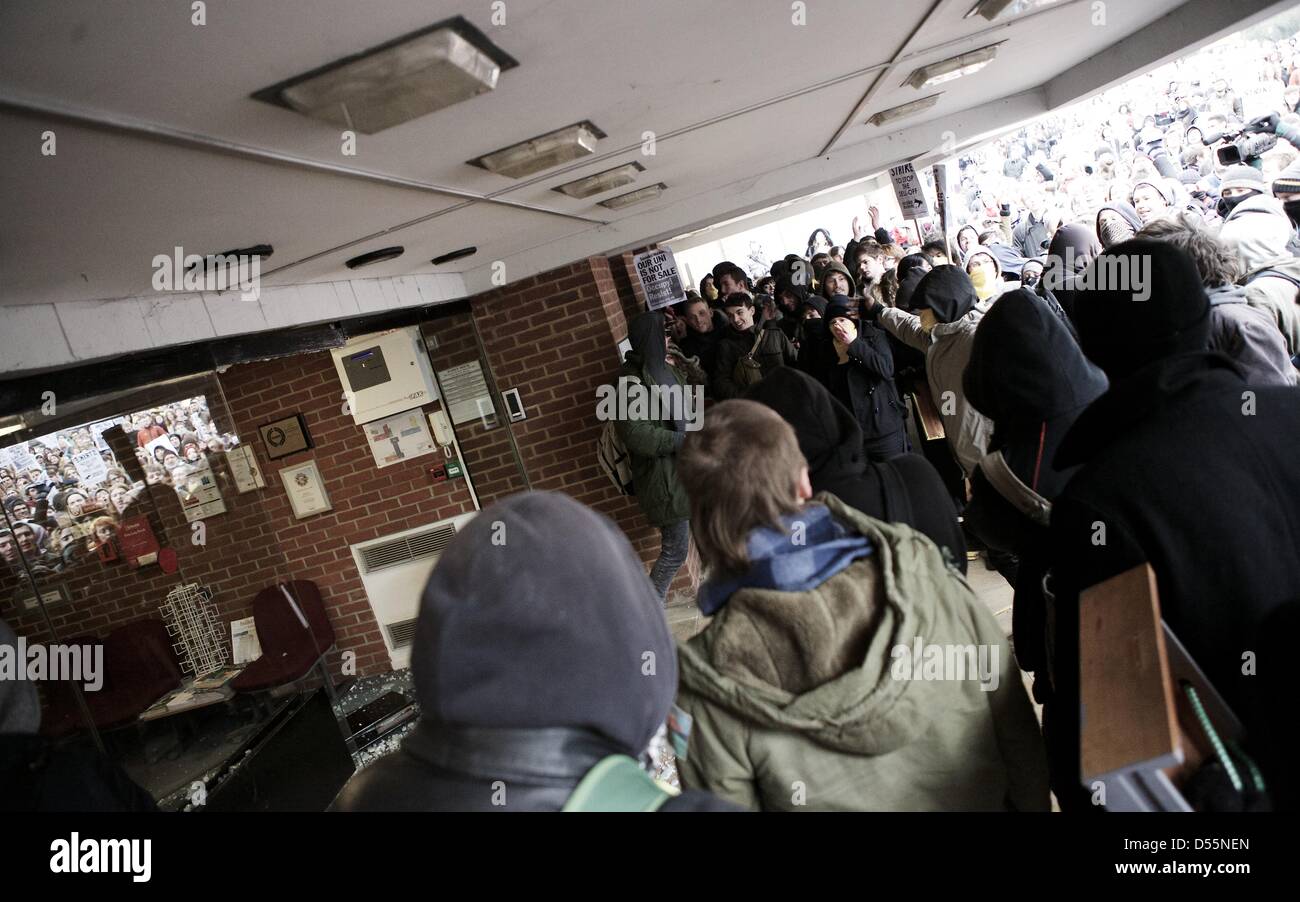 Brighton, Sussex, UK. 25 mars 2013. Les manifestants comme ils encourager smash avec succès une porte en verre, qui leur permettent d'avoir accès à un bâtiment de direction à l'Université Sussex. manifestants étaient en colère au cours de la privatisation prévue d'un certain nombre de services du campus qui selon les organisateurs, se traduirait par des pertes d'emploi. Bref des échauffourées ont éclaté pendant la journée entre la police et les manifestants et les "occupation", qui a fonctionné pendant plus d'un mois, se poursuit. Crédit : George Henton/Alamy Live News Banque D'Images