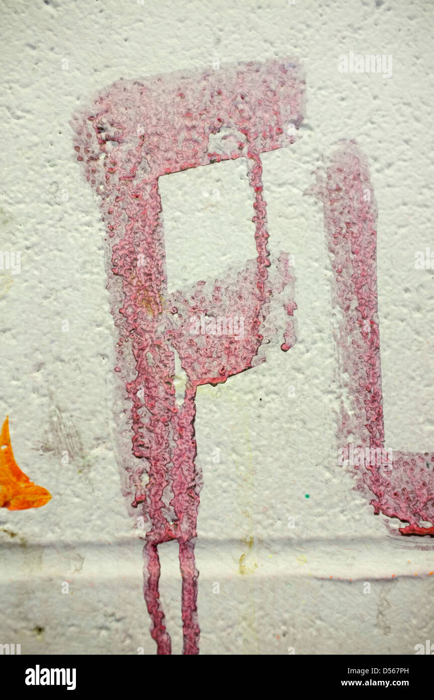 La lettre F peint sur mur blanc crème dans la peinture rouge avec les gouttes Banque D'Images