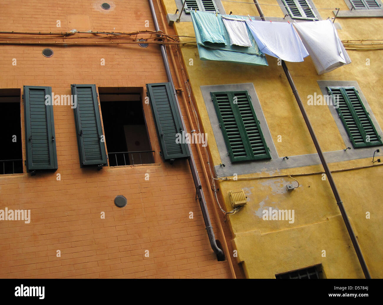 Orange et rouge en rangée de bâtiments anciens à Sienne, Toscane, Italie avec teal et blanc sur une corde à linge dans le vent Banque D'Images