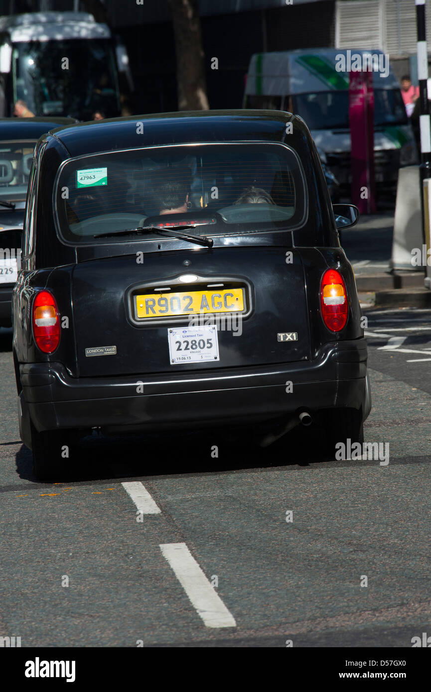 Black taxi cab roulant le long d'une rue dans la ville de Londres, en Angleterre. Banque D'Images