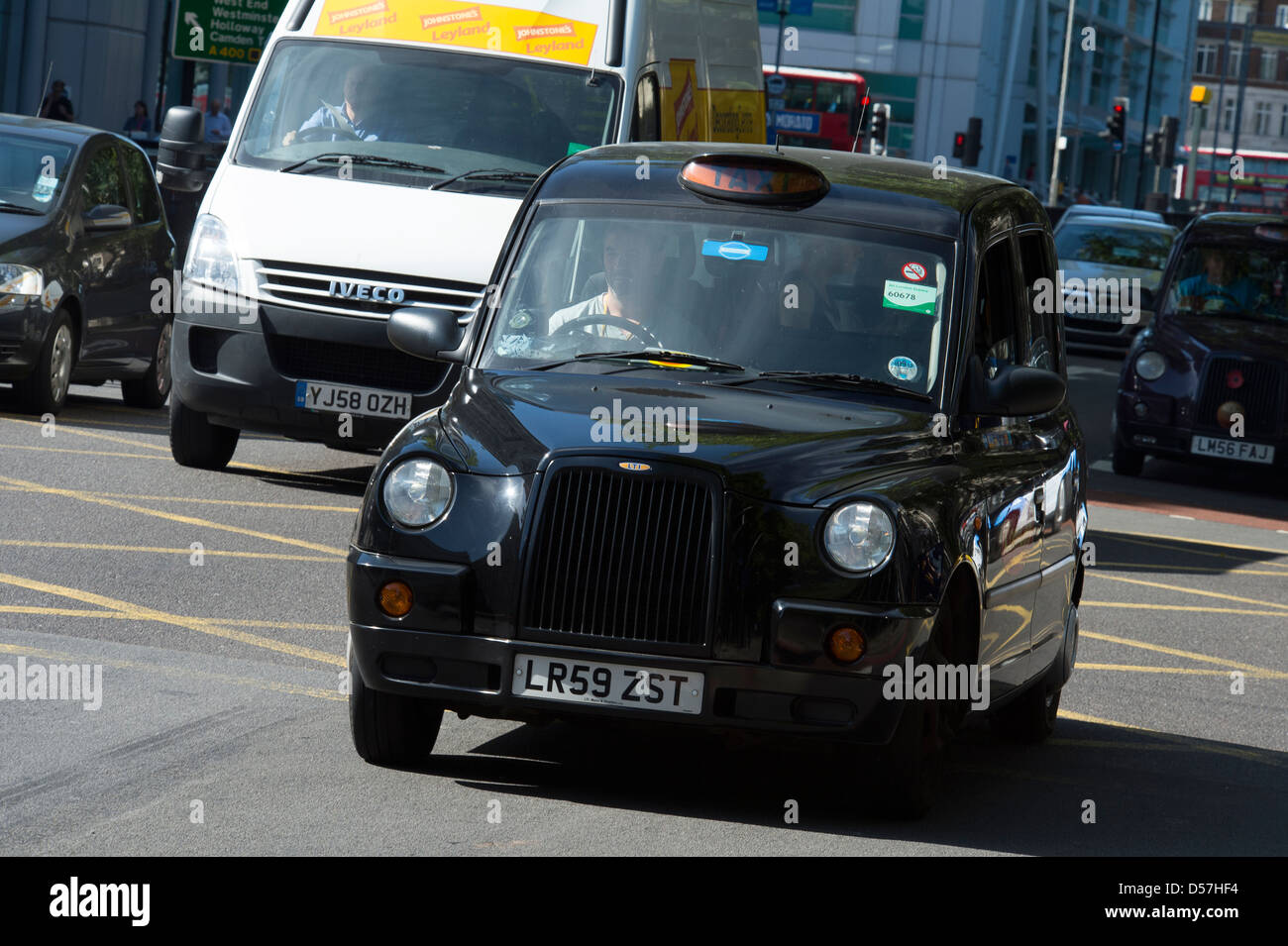 Black taxi cab roulant le long d'une rue dans la ville de Londres, en Angleterre. Banque D'Images