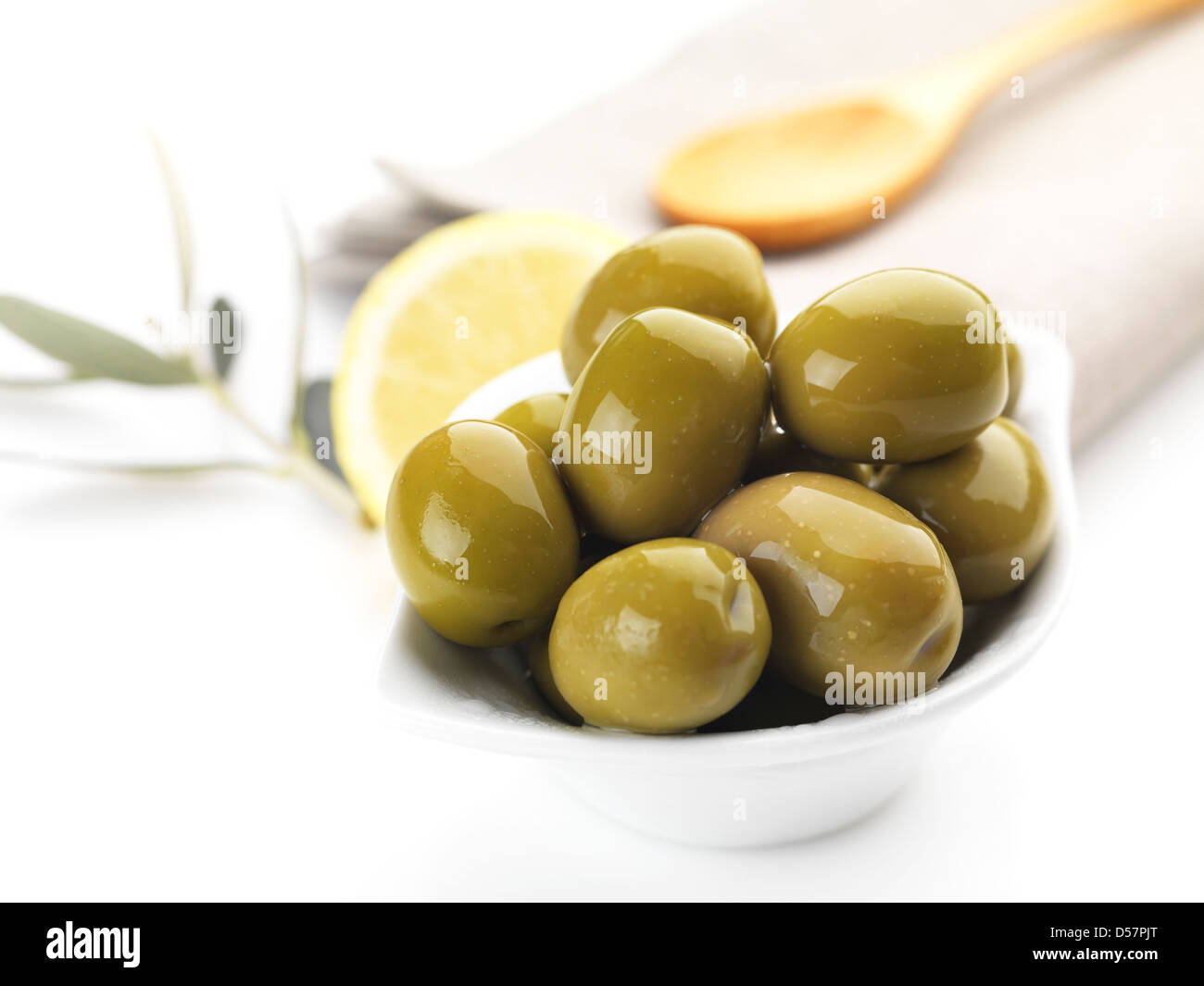 Olives vertes servi dans un bol et décoré avec une rondelle de citron et de feuilles d'olivier Banque D'Images