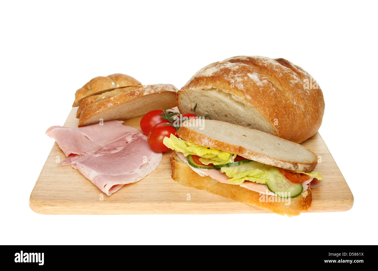Bloomer fraîchement cuits, pain, sandwich jambon et tomates sur une planche en bois isolés contre white Banque D'Images