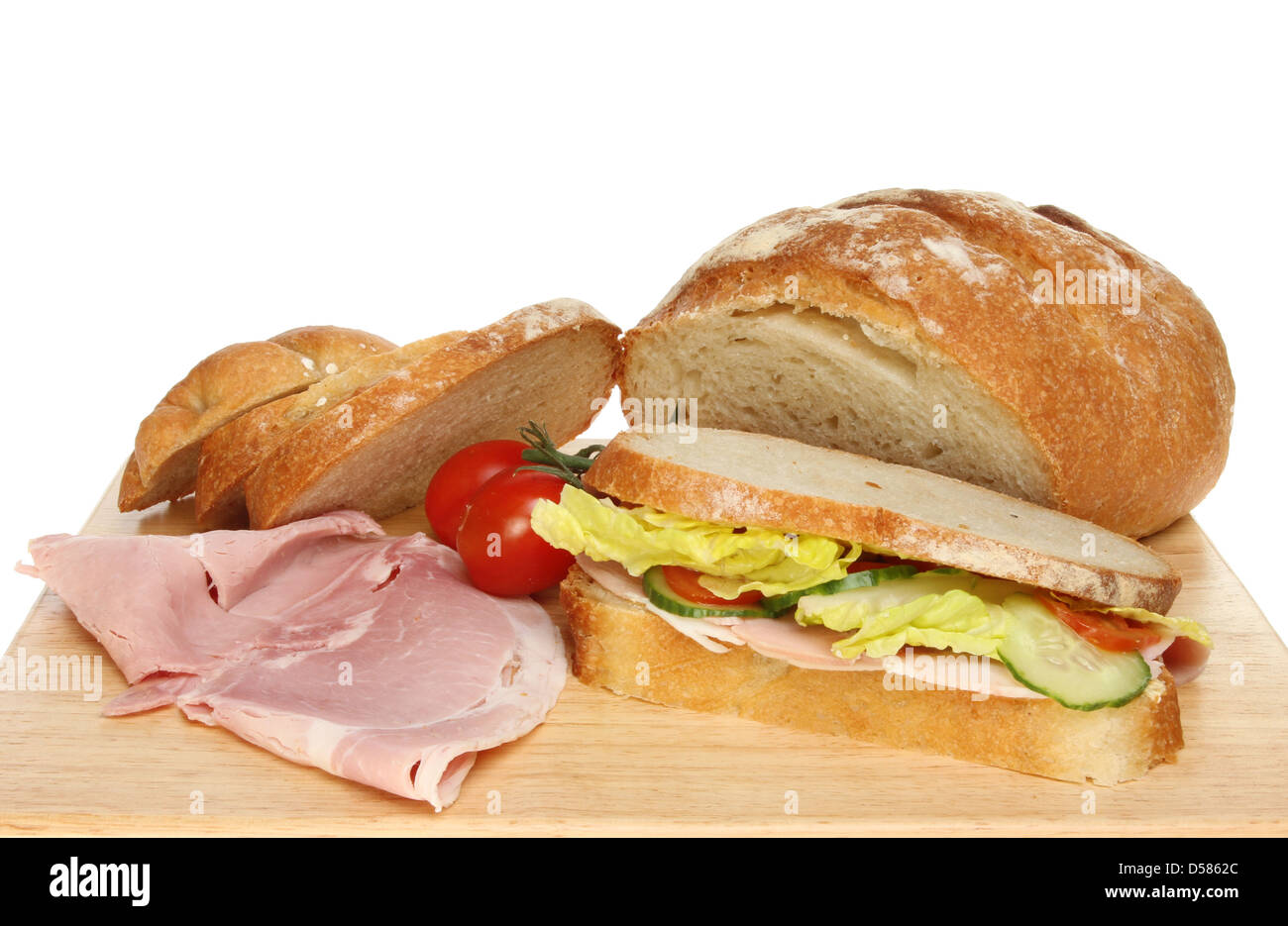 Libre d'un pain fraîchement cuit bloomer, sandwich au jambon et tomates sur une planche en bois Banque D'Images