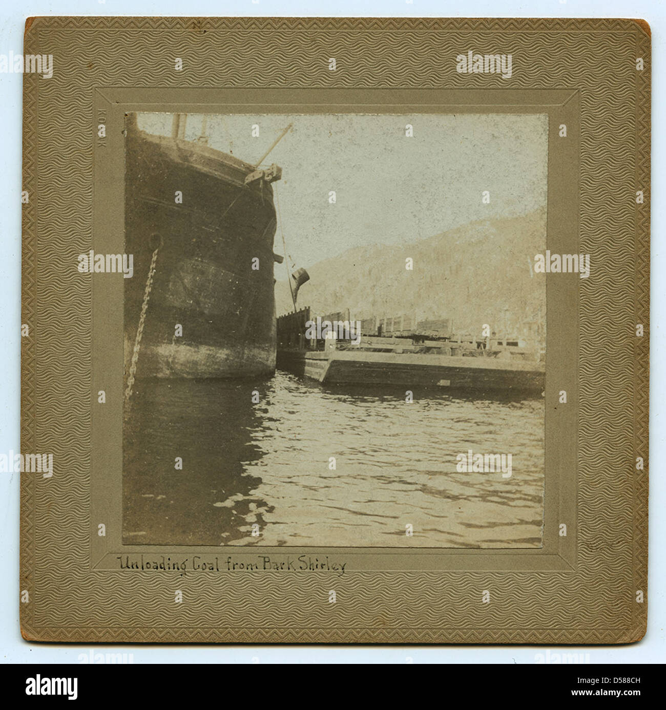 Charbon déchargé d'une écorce à Shirley, Alaska, dans une photographie historique. Cette image illustre l’importance du transport du charbon au début du XXe siècle et le rôle des industries maritimes dans la région. Banque D'Images