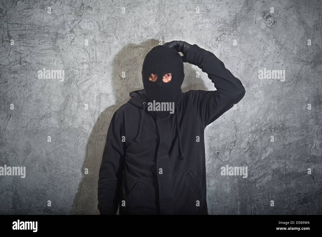 Concept, voleur cambrioleur confondu avec balaclava capturés et arrêtés devant le grunge mur de béton. Banque D'Images