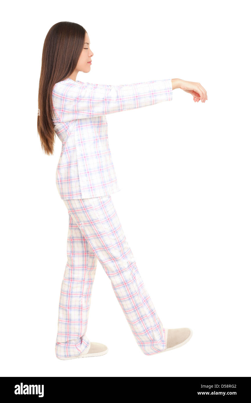 Voir le profil de young mixed race woman walking dans son sommeil en pyjama avec bras levés isolé sur fond blanc Banque D'Images