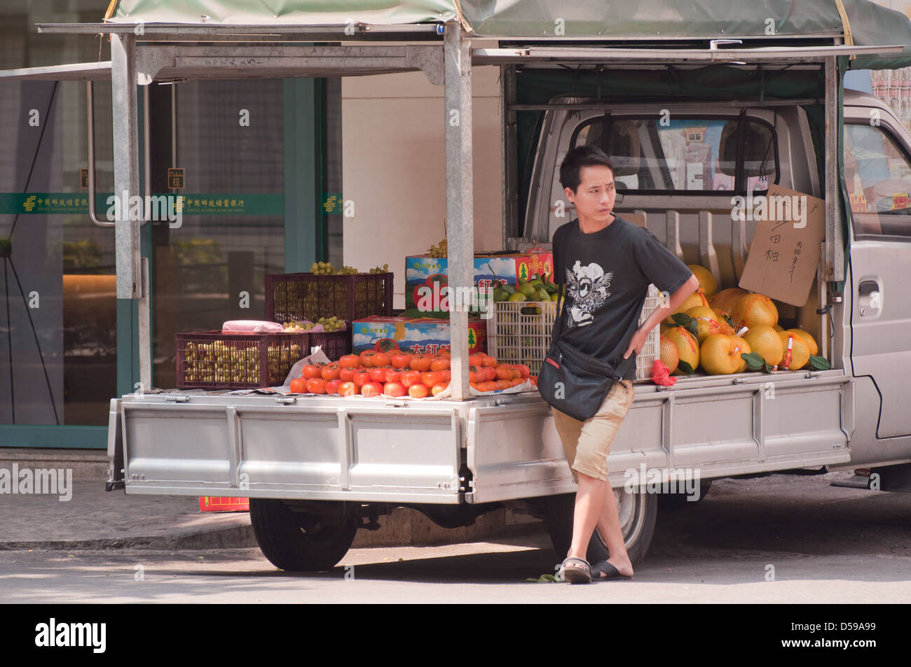 Un jeune Chinois colporteurs vendant des fruits, des fruits sur une petite voiture Banque D'Images
