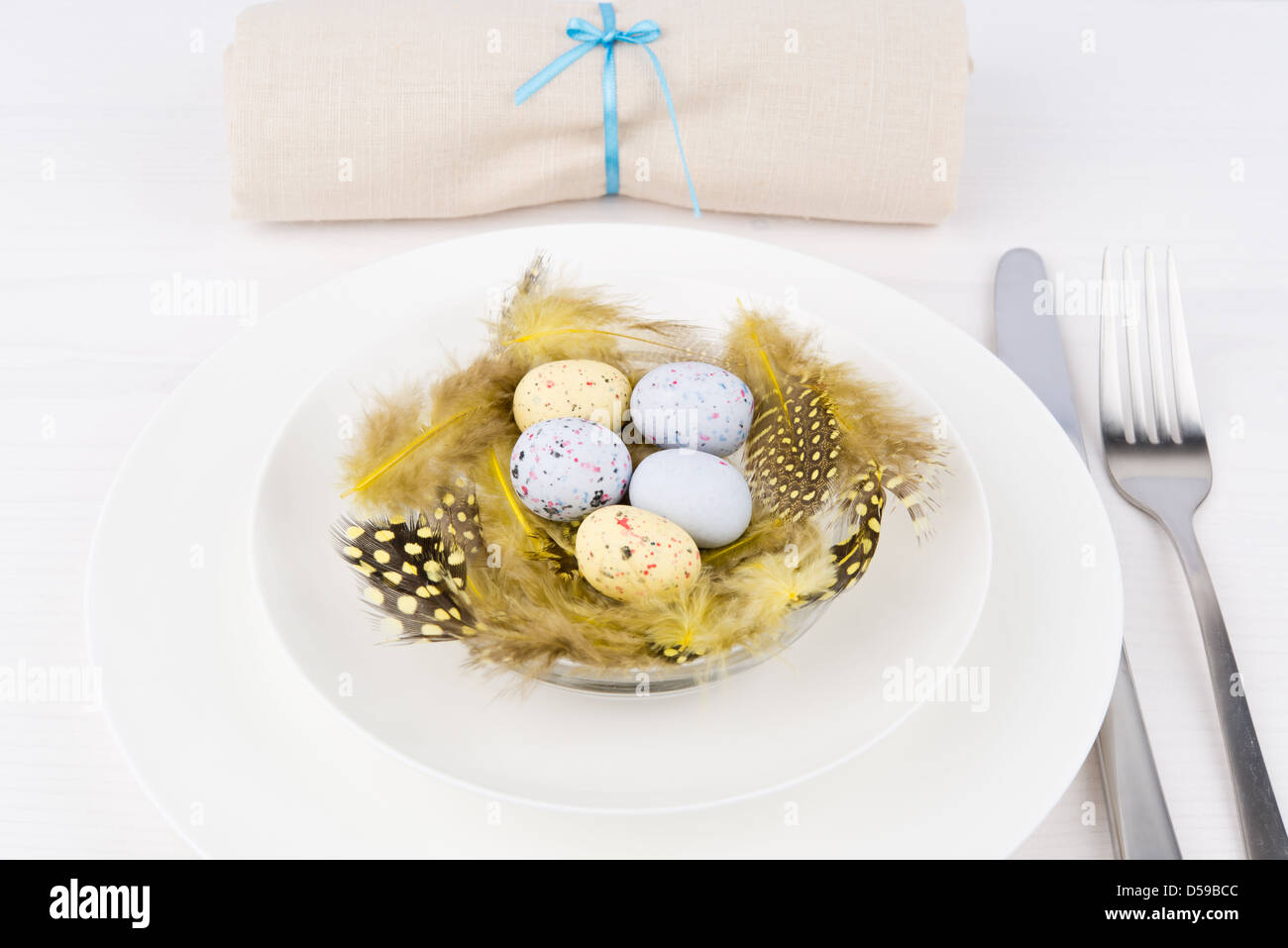 Table de Pâques pour un dîner de fête - un nid jaune décoratifs avec des oeufs d'ester sur une plaque Banque D'Images