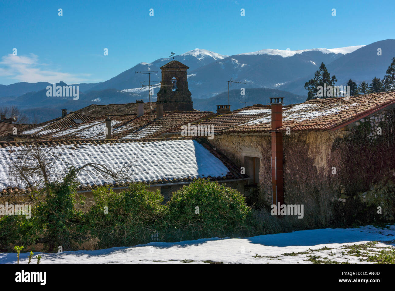 Vue vers les Pyrénées enneigés avec clocher de l'église et le toit de neige, ciel bleu Banque D'Images