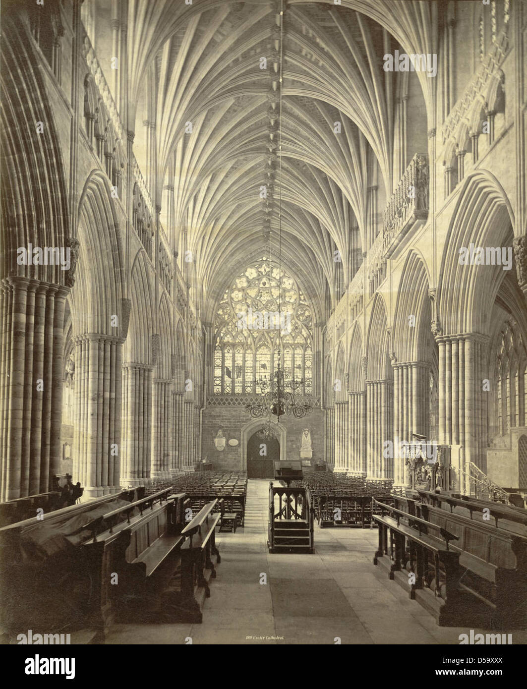 Une photographie de l'intérieur de la cathédrale d'Exeter en Angleterre, mettant en valeur son architecture gothique. L'image présente des colonnes groupées, des fenêtres à lancette, des voûtes nervurées et des roses, typiques de la conception de la cathédrale. Banque D'Images