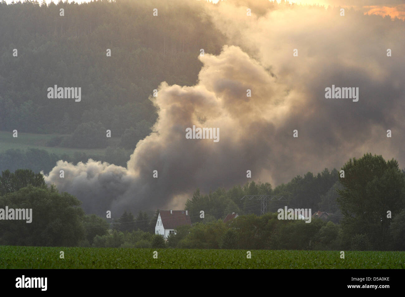 Une épaisse colonne de fumée monte dans le ciel au-dessus du village d'Foeritz, Allemagne, le 8 juillet 2010. Depuis les premières heures du matin, un entrepôt dans le village a été en feu. Les 50 fois 30 mètres de haut bâtiment a complètement en feu, un porte-parole de la police a déclaré à Saalfeld. L'entrepôt de bouteilles d'oxygène et d'accueillir le magnésium à l'origine aussi d'abord des explosions. Il n'en demeure pas uncla Banque D'Images