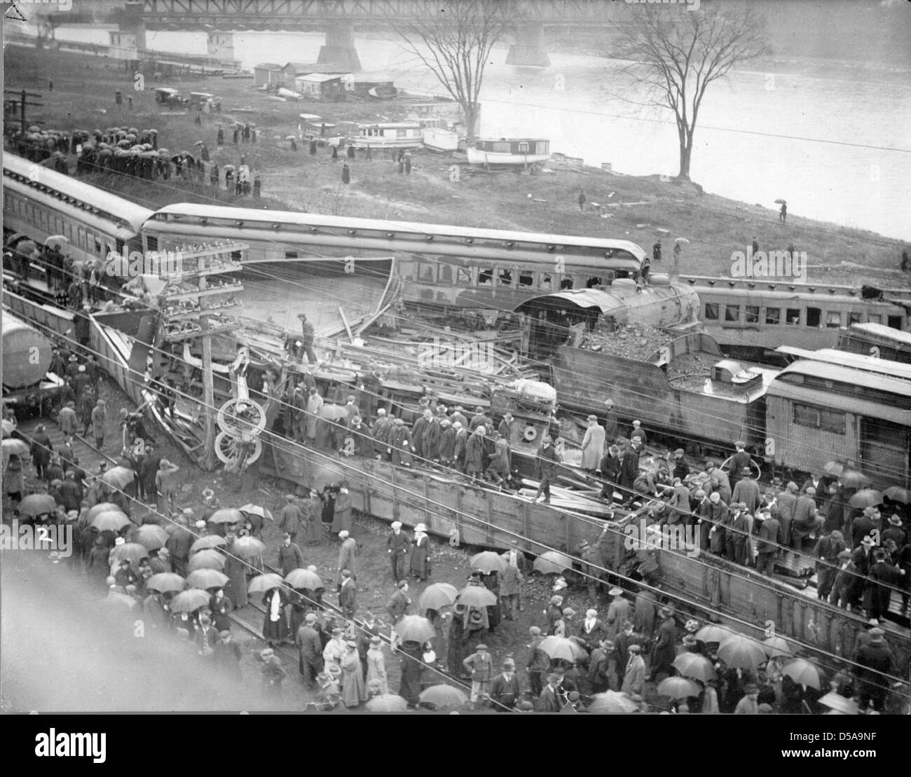 Une image historique d'une épave de train au bord d'une rivière, mettant en valeur les conséquences de l'accident. La photo souligne la nature destructrice des accidents ferroviaires et leur impact sur les transports au début du XXe siècle. Banque D'Images