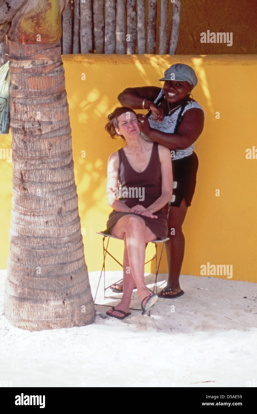 Les touristes d'une femme reçoit un tressage de cheveux sur Caye Caulker, Belize Banque D'Images