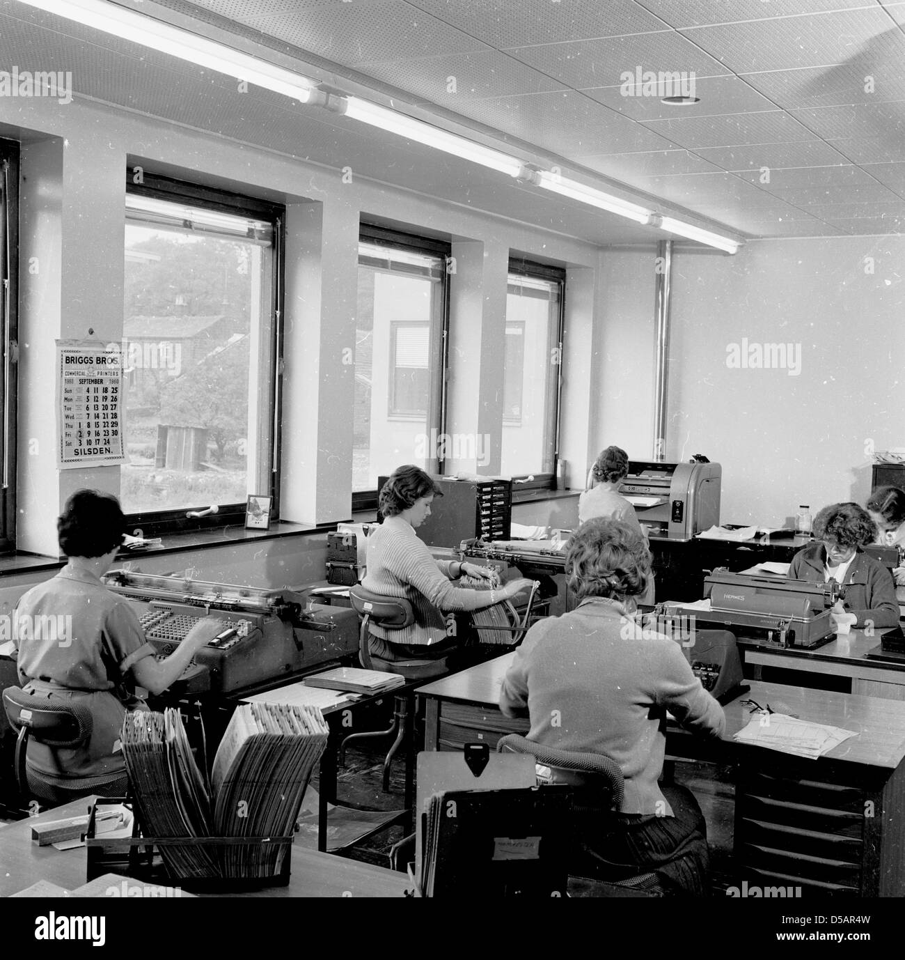 Tableau historique de l'Angleterre des années 60, des femmes qui travaillent dans un bureau à l'aide de télex ou de téléimprimeur machines. Banque D'Images