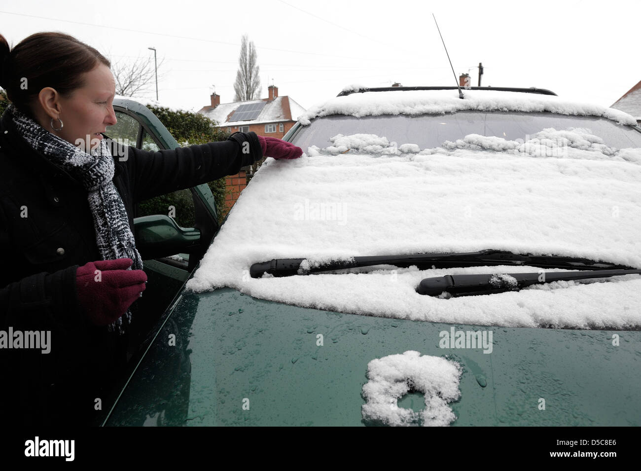 Une femme le déblayage de la neige à partir d'un pare-brise de voiture england uk Banque D'Images