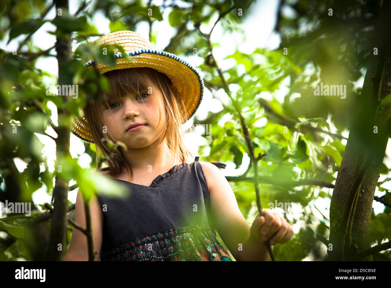 Peu jolie belle fille posant dans un chapeau de paille dans le parc. Banque D'Images