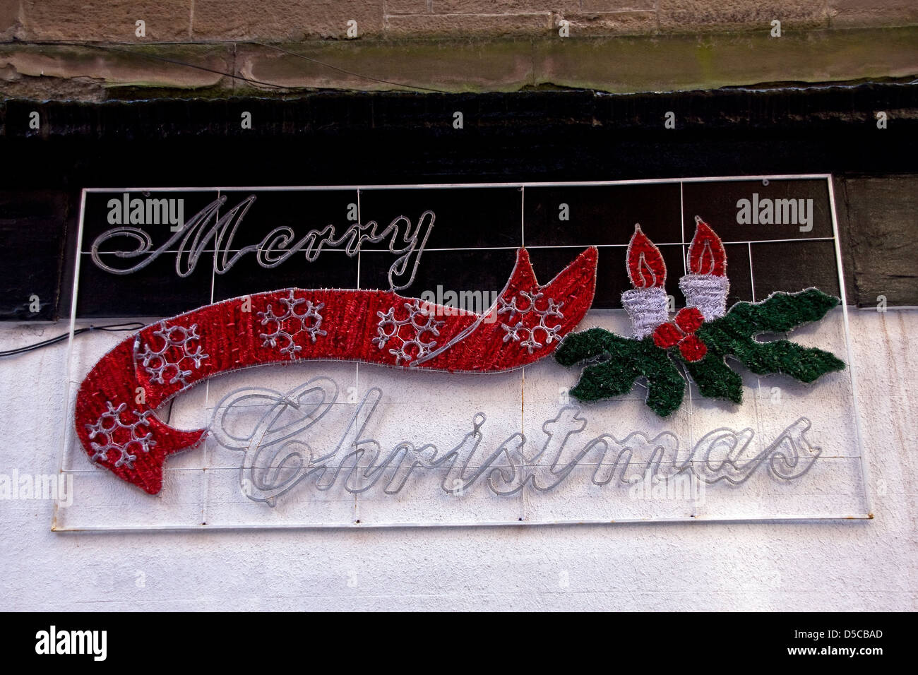 Joyeux Noël décorations encore accrochée sur un mur store Dundee à la fin mars 2013,UK Banque D'Images