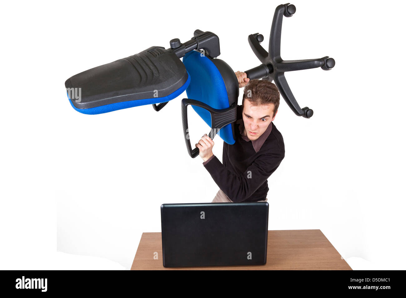 Jeune homme en colère qui se tenaient au-dessus d'un ordinateur portable avec une chaise de bureau de la préparation pour le détruire Banque D'Images