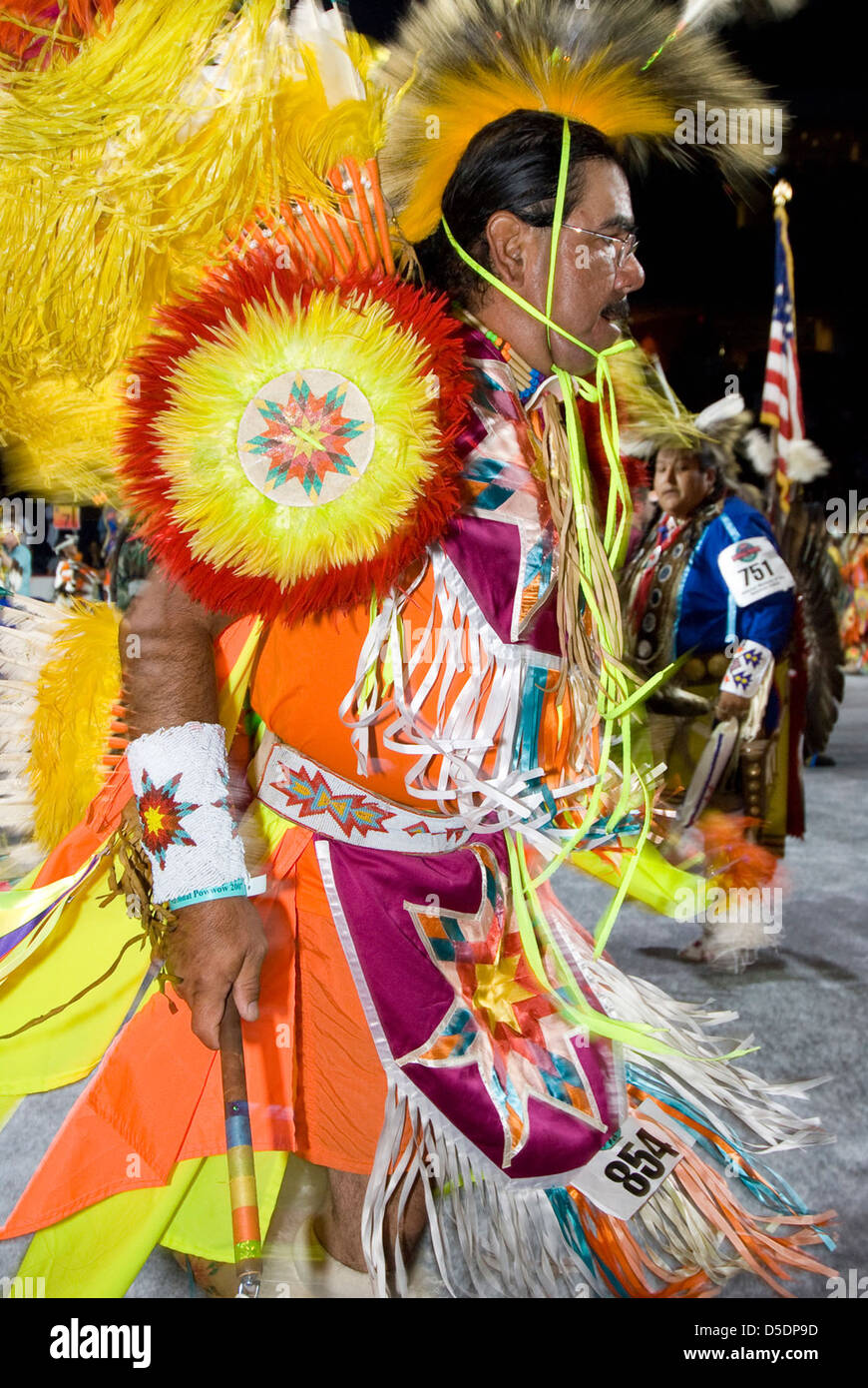 Photographie d'une cérémonie de pow-wow amérindienne, mettant en vedette un danseur dans des regalia traditionnelles tenant un drapeau américain. L'événement célèbre la culture amérindienne, avec la danse ancestrale symbolisant un lien avec le patrimoine et la tradition. Banque D'Images