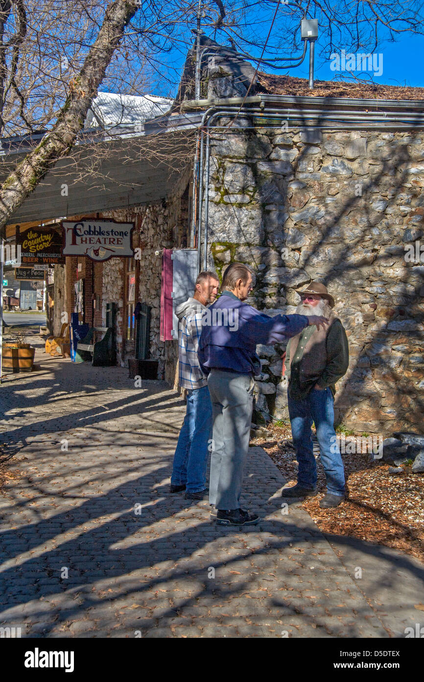 Ombragée par des branches d'arbre, trois hommes à l'extérieur de converse un ancien magasin général et le théâtre en volcan, CA. Banque D'Images