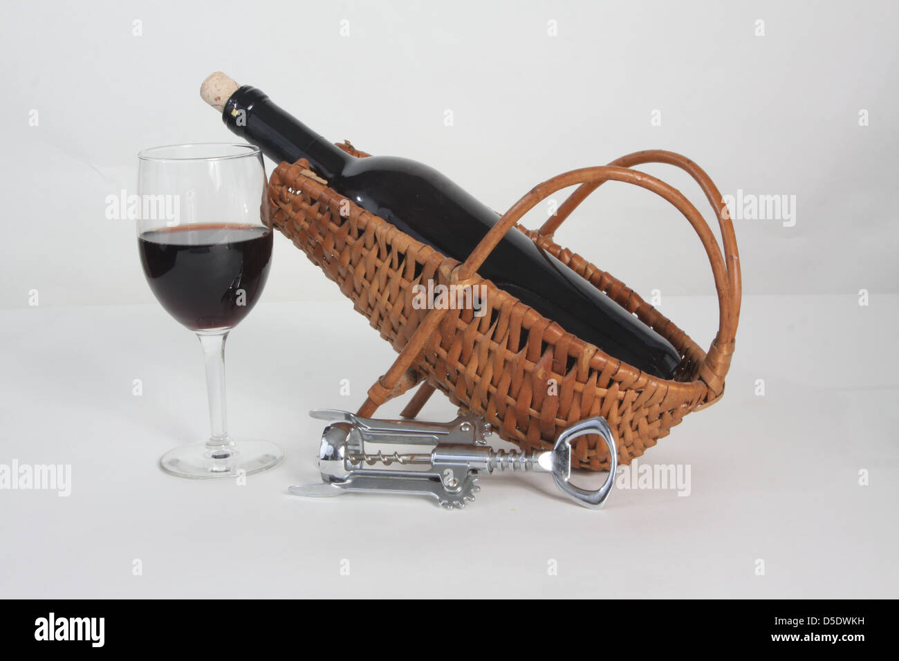 Bouteille de vin rouge dans une bouteille en osier berceau et un verre de vin. Banque D'Images