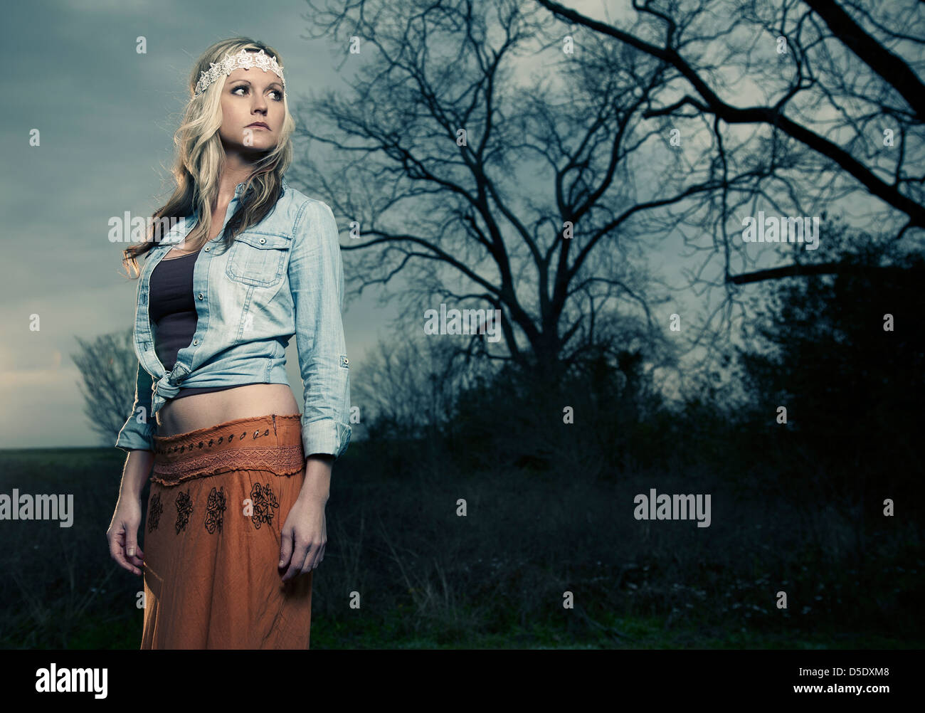 Femme robe sixties standing in field against sky Banque D'Images