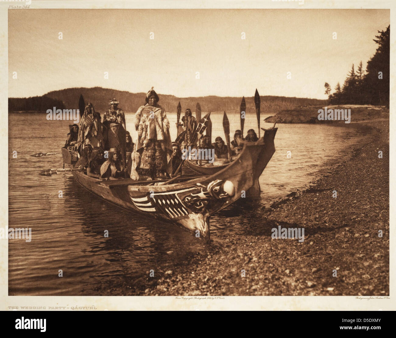 Une fête de mariage amérindien Qagyuhl du début des années 1900 est représentée sur cette photographie d'Edward Curtis. La fête est montrée dans un canoë décoré sur un lac, avec des regalia tribaux et des lances présentes. Banque D'Images