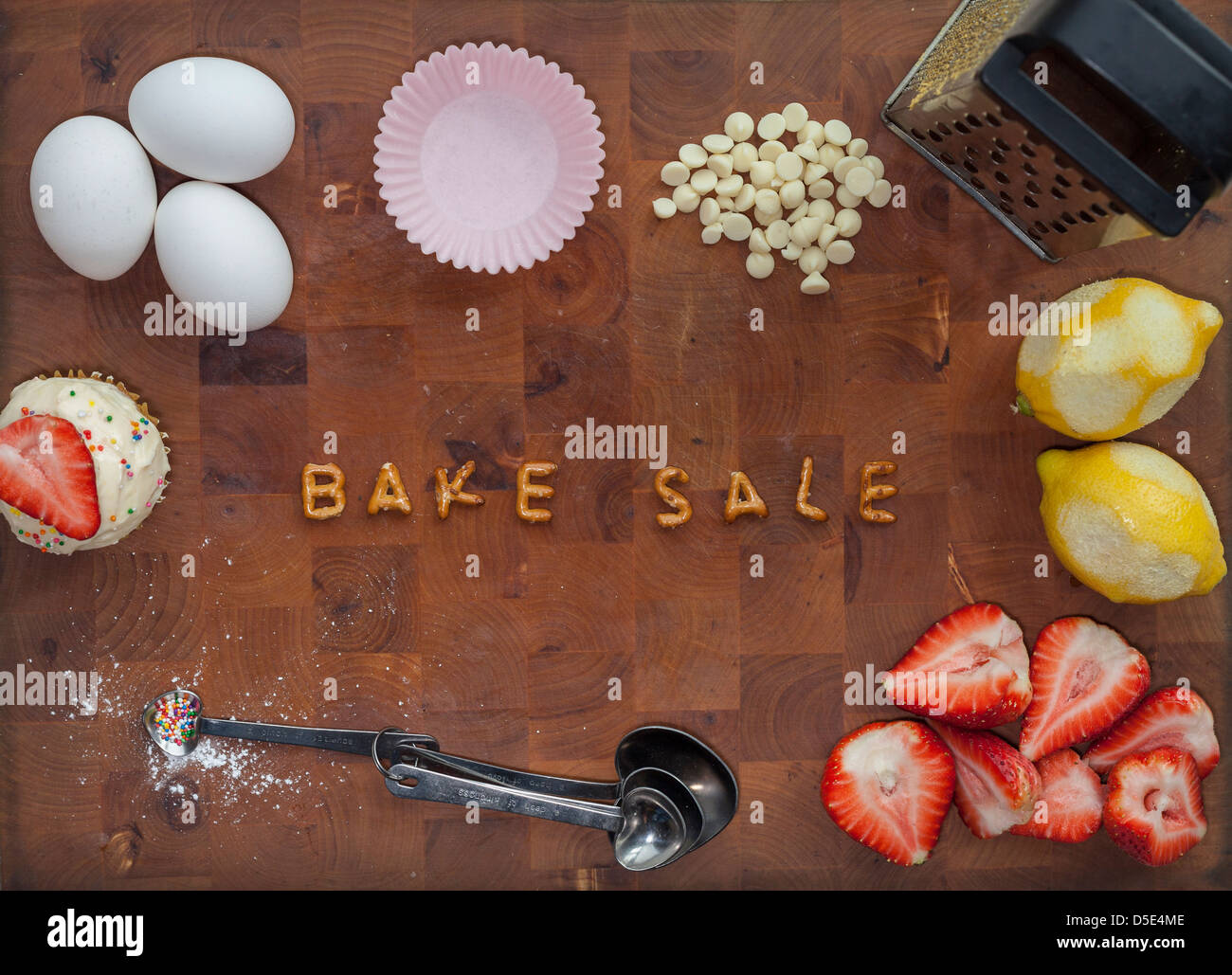'Vente de pâtisseries" énoncé dans les lettres sur une planche entouré par des cuillères, cupcake, œufs, citron et fraise. Banque D'Images