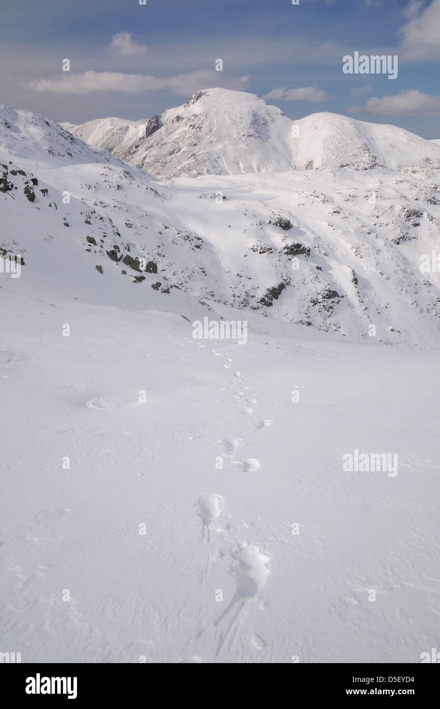 Des traces de pas dans la neige sur les rochers avec Seathwaite Allen tomba Grand Gable et Green Gable en arrière-plan, Lake District Banque D'Images