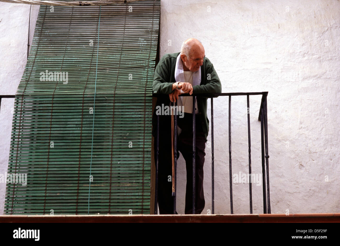 Vieil homme debout sur un balcon avec volets en bois vert à Ronda andalousie le Sud de l'Espagne Banque D'Images