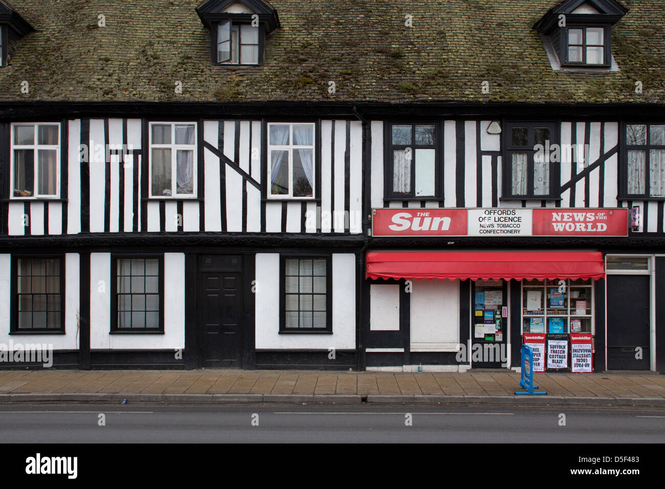 Un marchand qui occupent une partie d'un bâtiment de style Tudor et de promouvoir le soleil et les News de journaux, à Ipswich, Suffolk. Banque D'Images