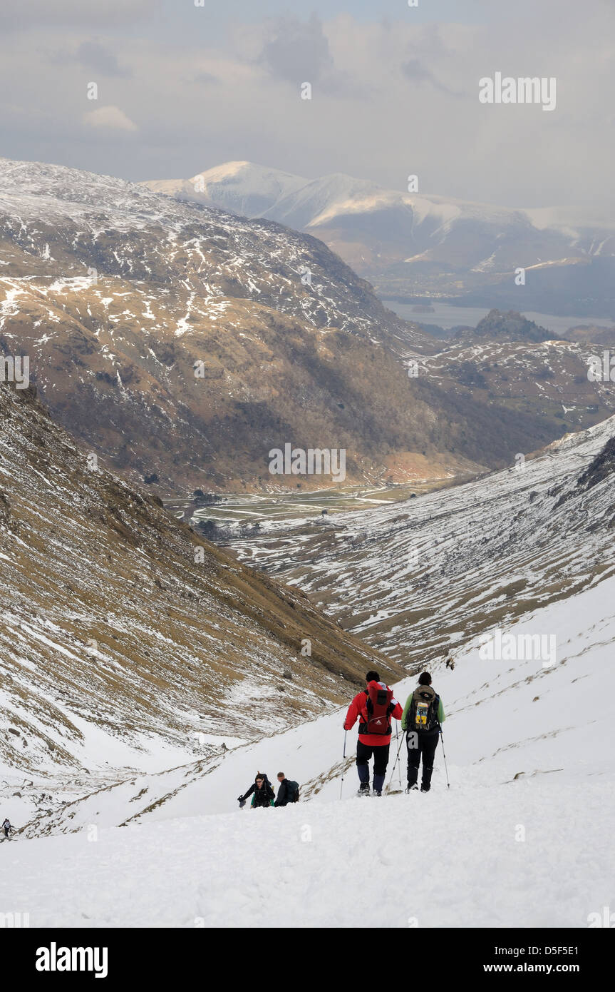 Les marcheurs en ordre décroissant le chemin par Grains Gill en hiver dans le Lake District, vue sur Skiddaw à Borrowdale Banque D'Images