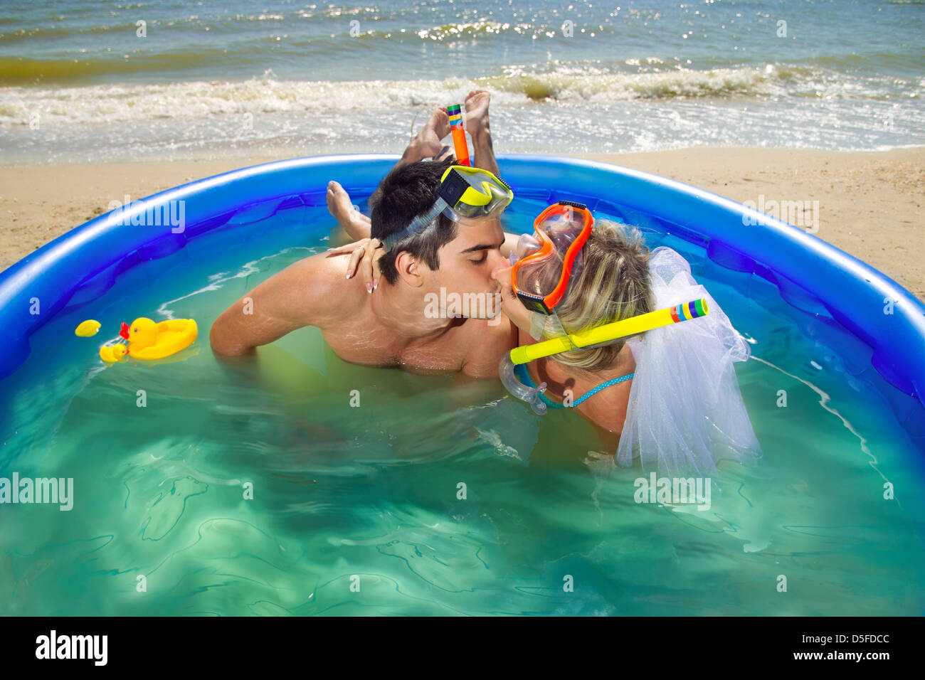 Un jeune et beau couple de jeunes mariés sur la plage de piscine Banque D'Images