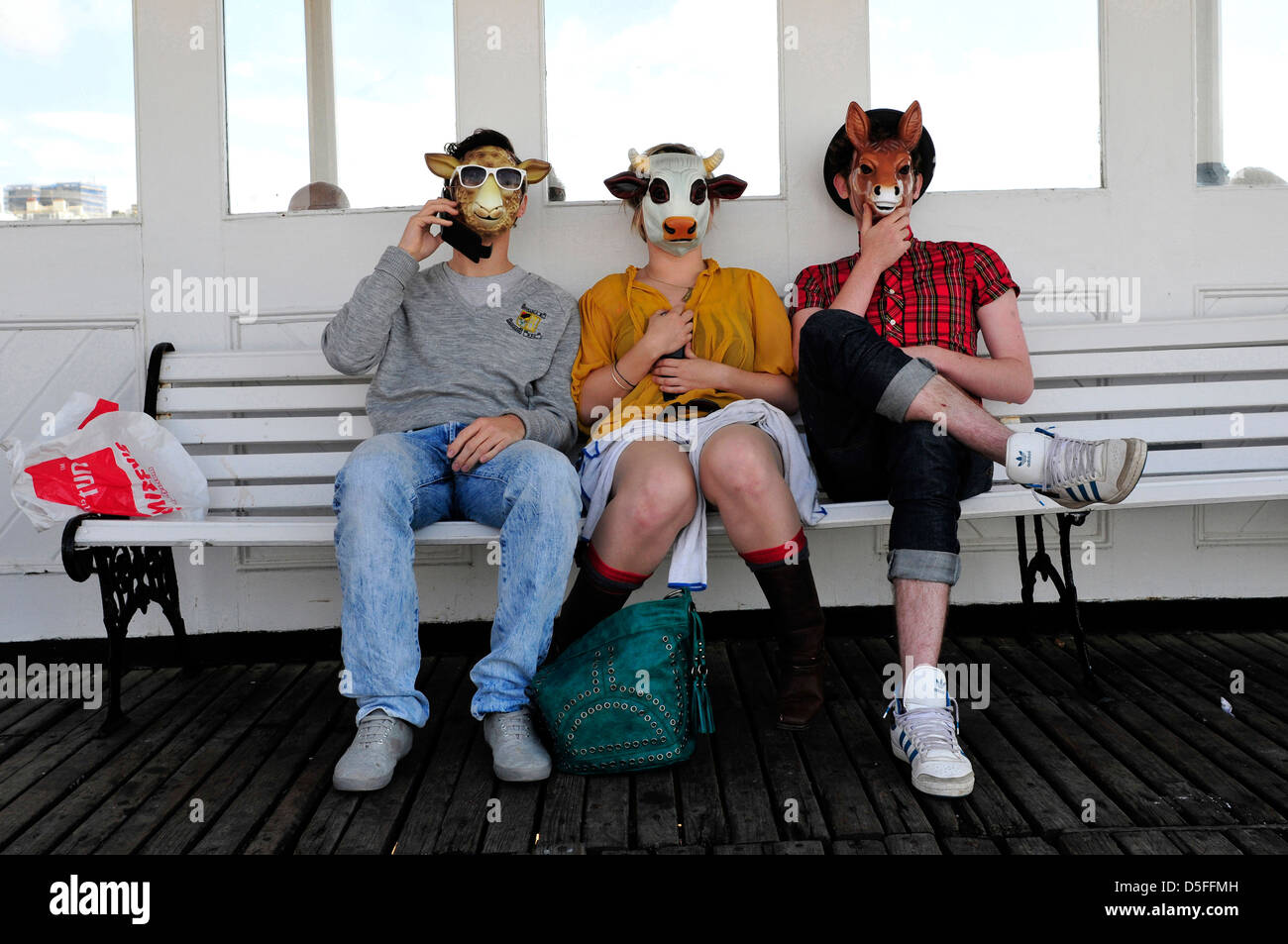 Trois personnes assises sur un banc portant des masques, la jetée de Brighton, Royaume-Uni. Banque D'Images