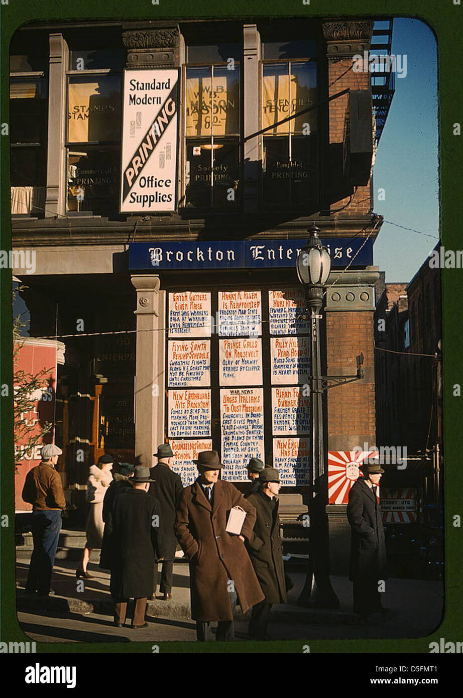 Une image historique montrant les gros titres affichés dans une vitrine au coin de la rue du bureau du journal Brockton Enterprise à Brockton, Massachusetts. La scène reflète l'ère des années 1940, capturant un moment de l'histoire américaine. Banque D'Images