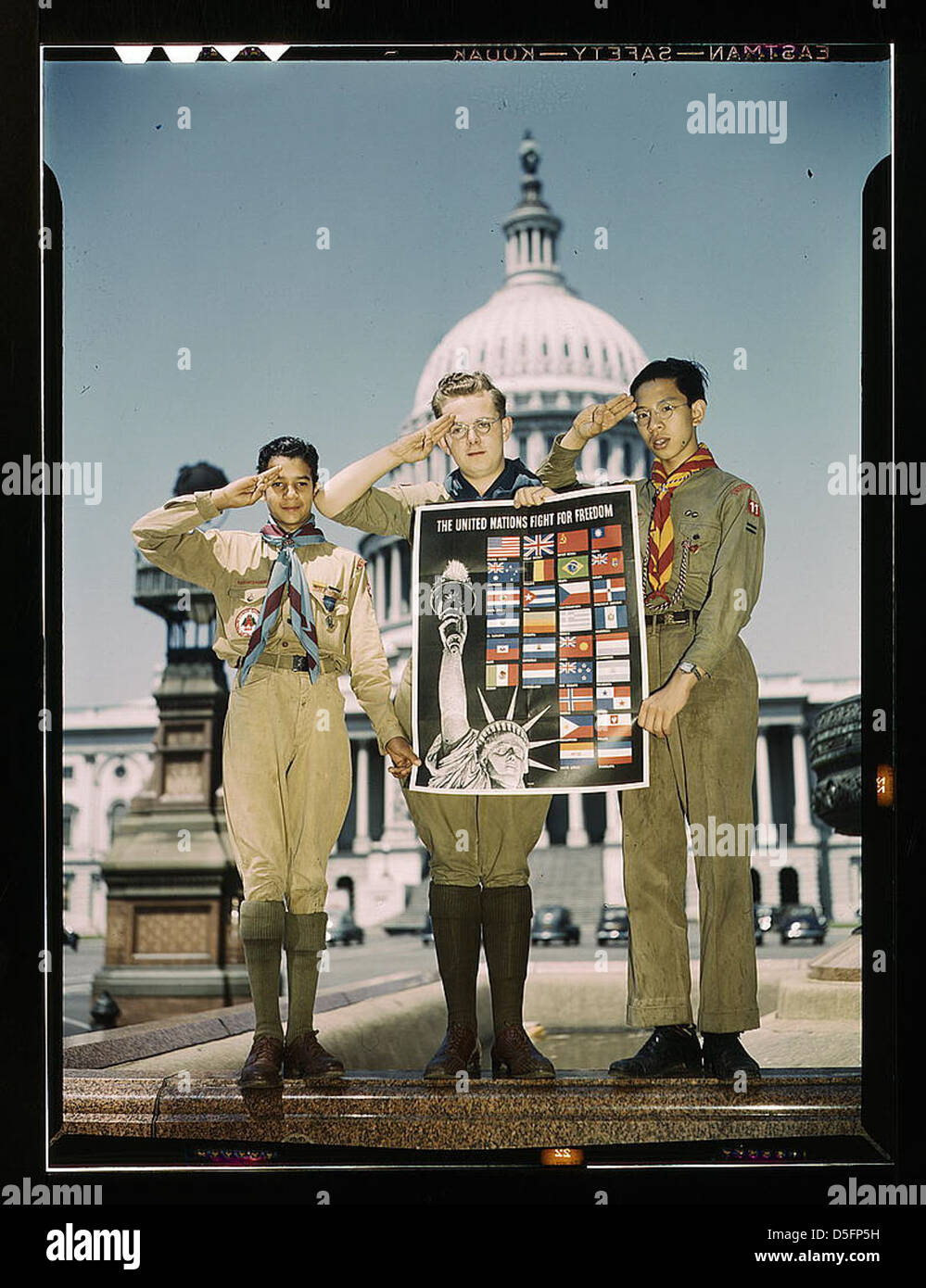 Une photographie des années 1940 montrant des scouts de diverses origines raciales devant le Capitole des États-Unis, livrant une affiche pour soutenir l'effort de guerre pendant la IIe Guerre mondiale L'image reflète la diversité et l'effort collectif de la jeunesse américaine pendant la guerre. Banque D'Images
