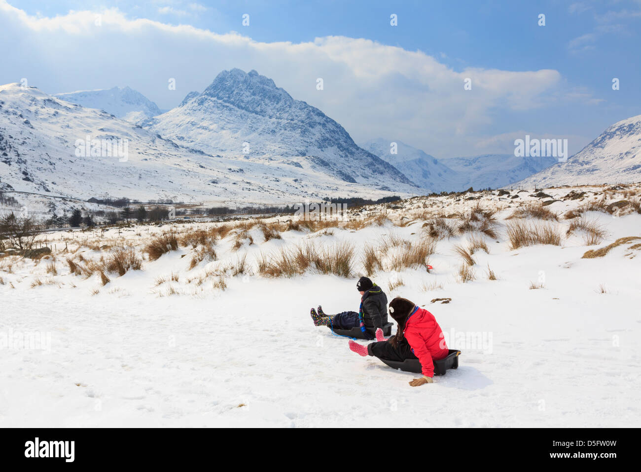 Les enfants de la luge dans la région de montagnes de Snowdonia National Park par temps froid et d'importantes chutes de neige. Ogwen Valley, au nord du Pays de Galles, Royaume-Uni Banque D'Images