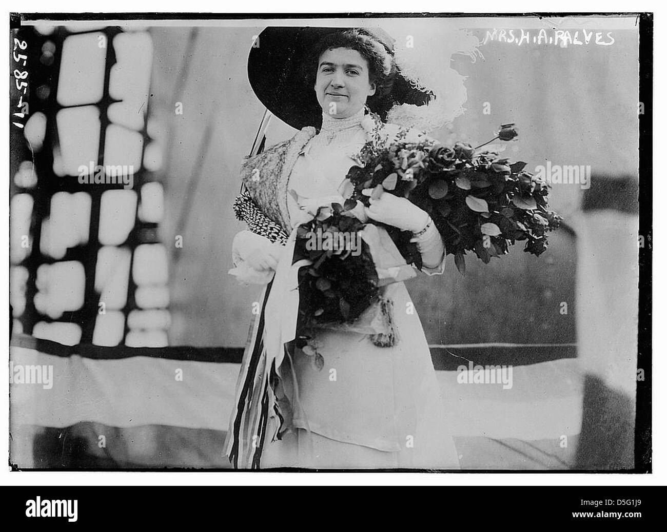 Un portrait de MRS H.A. Ralves, la représentant tenant un bouquet de fleurs, portant une robe blanche, et ornée de plumes d'autruche dans son chapeau. La photographie capture l'élégance de la mode du début du XXe siècle. Banque D'Images