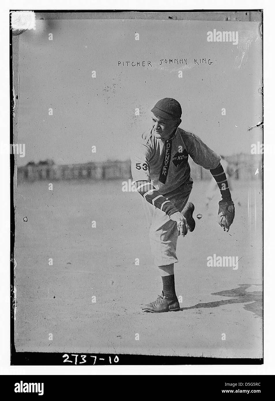 Cette image montre Johnny King, un lanceur de baseball de Denver, capturé en action alors qu'il lançait un terrain. Son uniforme et sa posture reflètent le style athlétique de l'époque. Banque D'Images