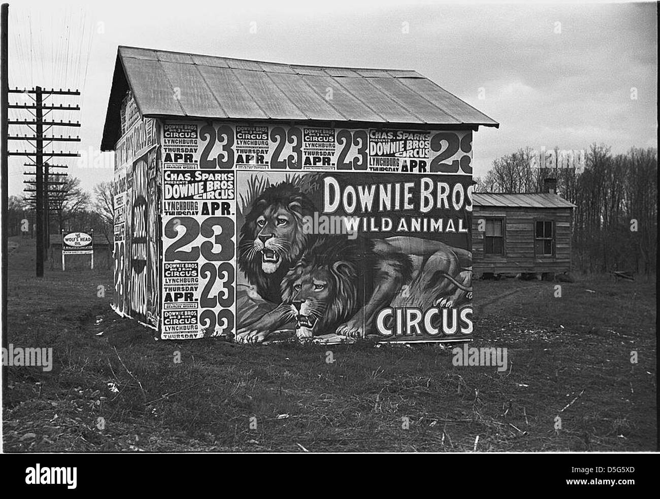 Photographie d'un bâtiment à Lynchburg recouvert d'affiches faisant la publicité du cirque Downie Bros, capturant une scène publicitaire vintage du milieu du XXe siècle. Banque D'Images