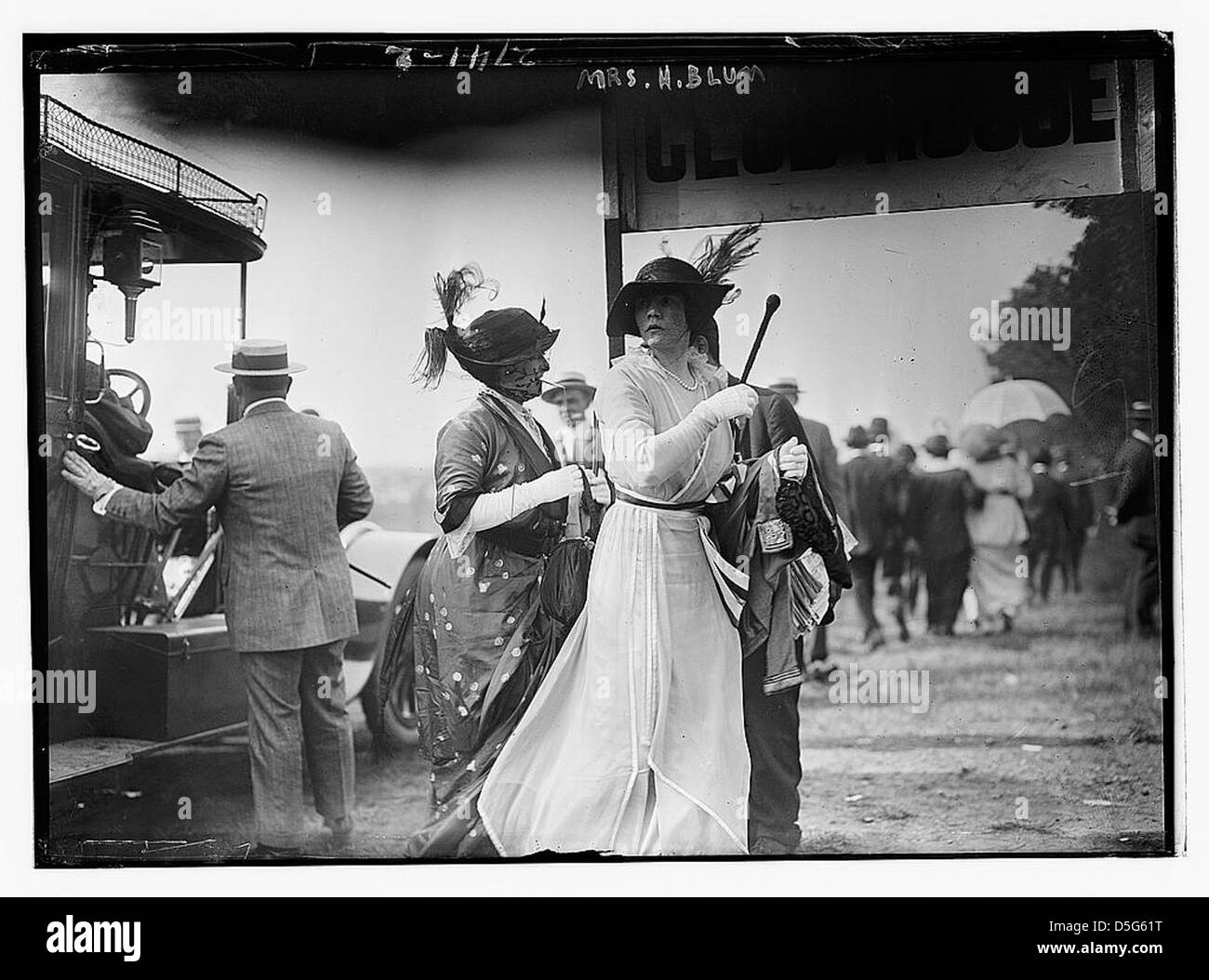Cette photographie du début du XXe siècle montre MRS H. Blum lors d'un spectacle équestre, vêtue d'une robe blanche et d'un chapeau à la mode. L'image met en évidence la vie sociale à la mode des femmes au début des années 1900 et le passe-temps populaire des courses de chevaux. Banque D'Images