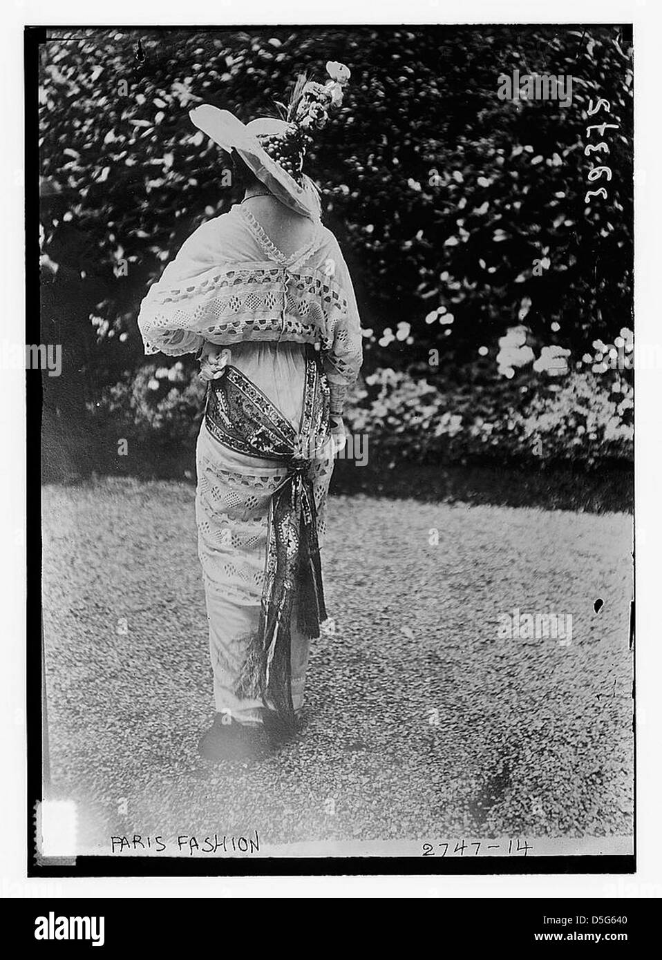 Cette photographie du XXe siècle montre une femme portant une robe élégante et un chapeau à l'extérieur à Paris, mettant en valeur les tendances de la mode du milieu du siècle dans un cadre élégant et sophistiqué. Banque D'Images