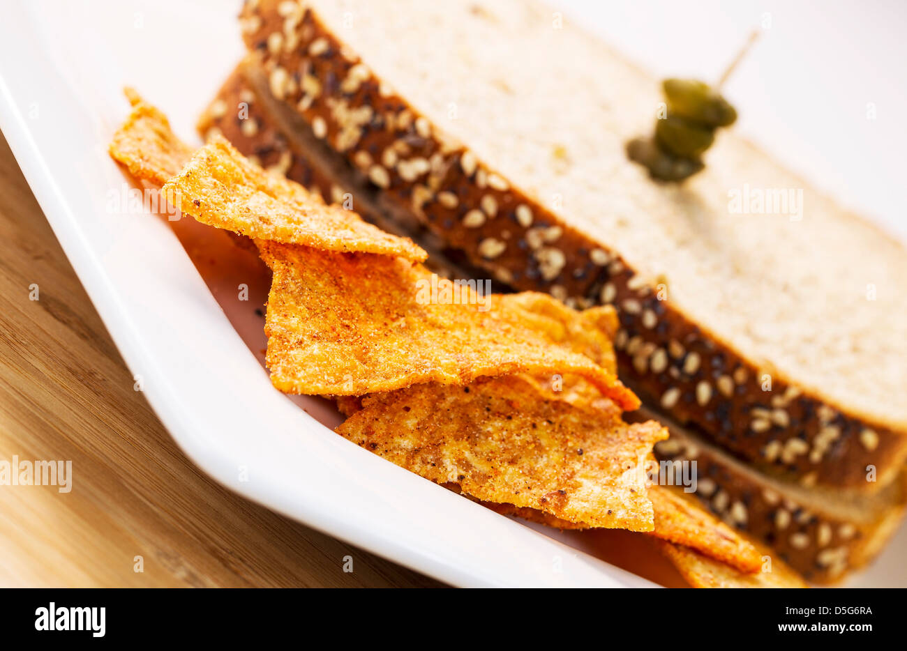 Photo horizontale de jetons d'or en face de blé entier sandwich sur plaque blanche avec bambou naturel bois sous Banque D'Images