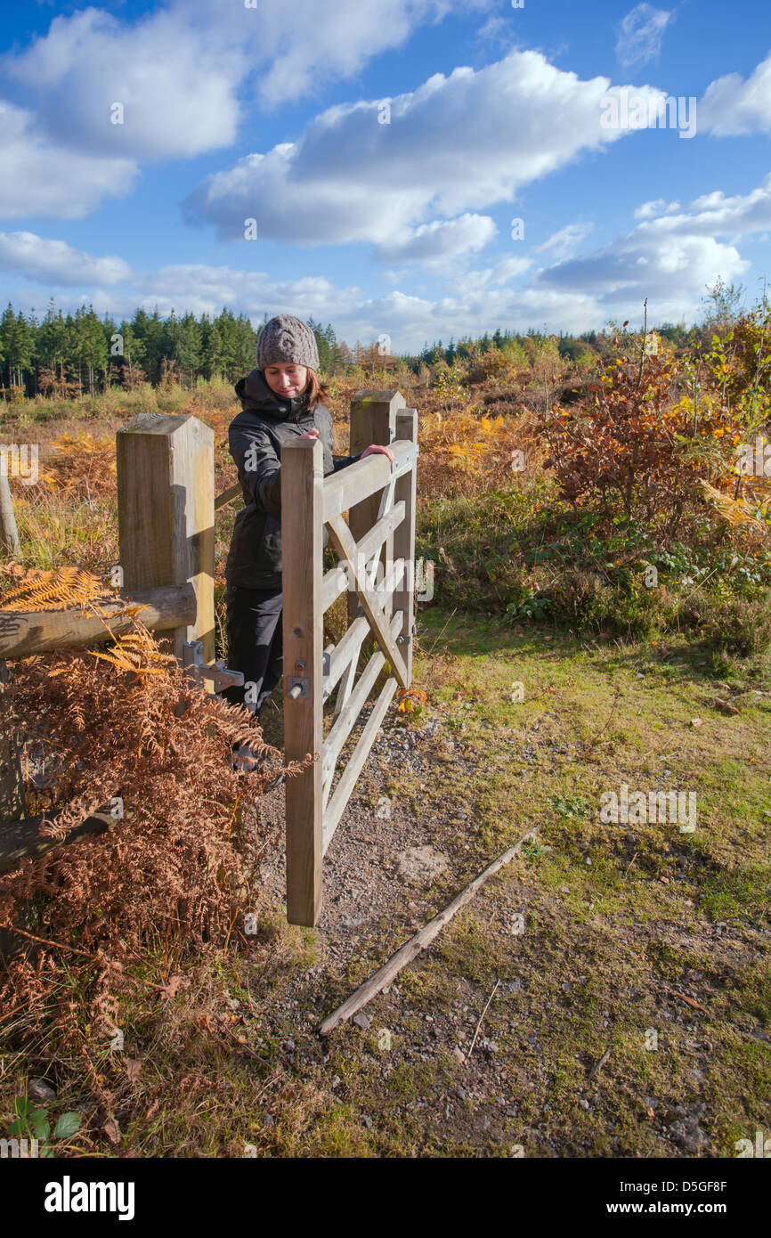 Jeune femme de l'ouverture d'une porte en bois restauré sur la lande. Banque D'Images