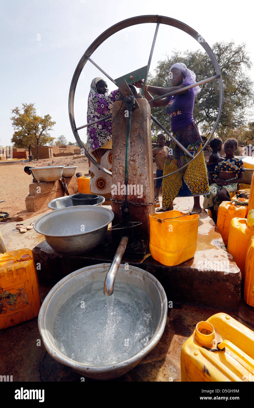 Les femmes tourner la roue d'une pompe à eau dans un village, le Burkina Faso, l'Afrique Banque D'Images