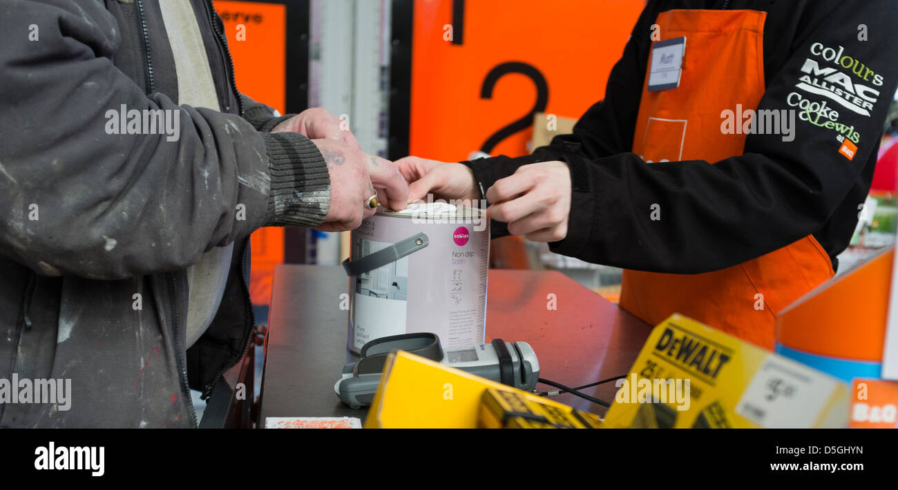 Un homme d'acheter un pot de peinture dans une boutique assistant à une succursale de B&Q DiY superstore boutique société de vente au détail de matériel UK Banque D'Images